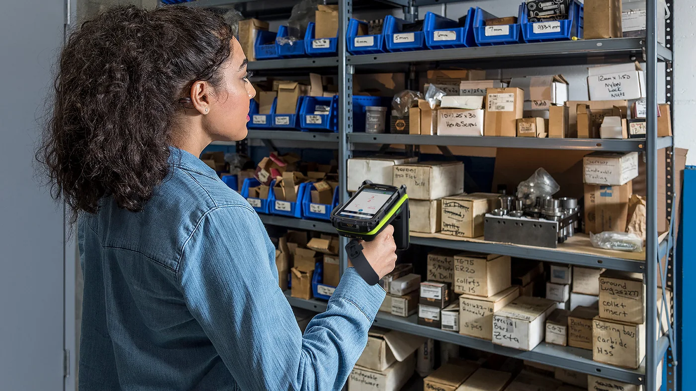 Colaboradora utilizando un lector RFID Zebra para revisar artículos en un almacén.