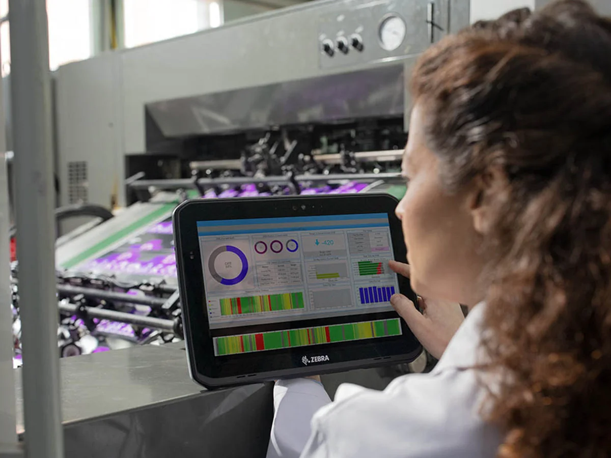 Operadora consultando información de una máquina con una tableta Zebra en manufactura.